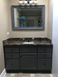 Dark bathroom sink cabinet with a large mirror