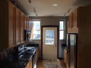 Small narrow kitchen with dark counter and brown cabinet