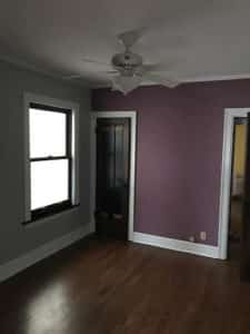 A empty purple room with a ceiling fan