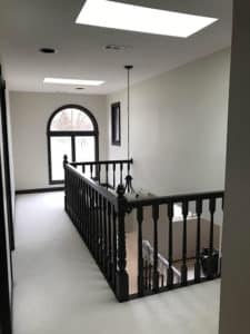 Second floor hallway with white flooring and a chandelier