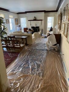Man putting plastic coverings on floor of living room