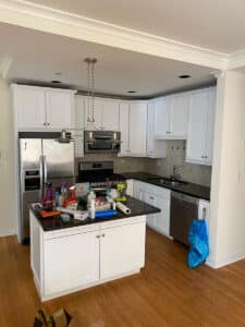 Angled shot of kitchen with island and white cabinets
