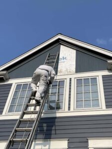 Man on ladder on side of house