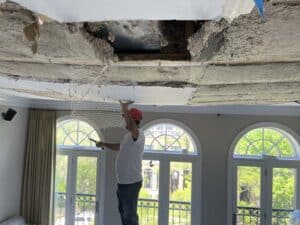 Man working above hole in ceiling
